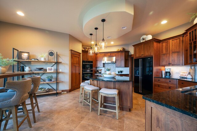 kitchen with pendant lighting, a kitchen bar, tasteful backsplash, and black appliances