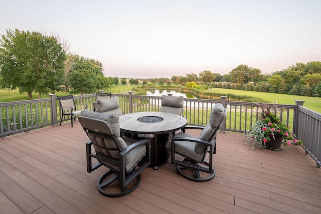 deck at dusk with a water view and a yard