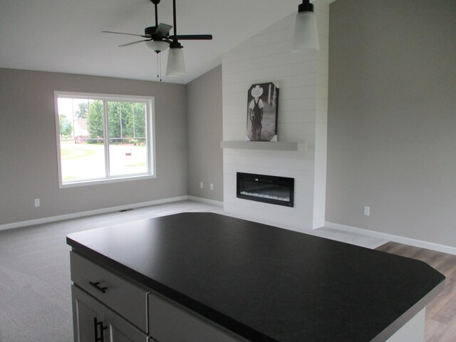 kitchen with a fireplace, gray cabinets, light carpet, ceiling fan, and vaulted ceiling