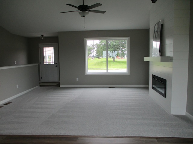 unfurnished living room with ceiling fan, carpet flooring, and a fireplace