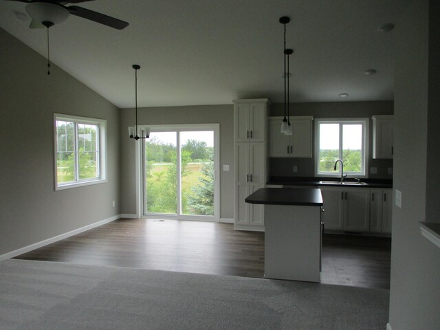 kitchen featuring dark hardwood / wood-style flooring, a kitchen island, sink, white cabinetry, and decorative light fixtures