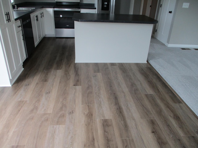 kitchen with wood-type flooring, white cabinets, dishwasher, and stove