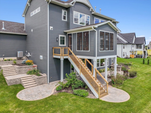 rear view of house with a patio, a sunroom, a lawn, and cooling unit