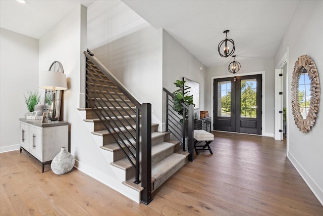 foyer featuring french doors, light hardwood / wood-style floors, and an inviting chandelier