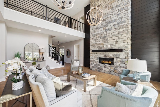 living room featuring a towering ceiling, an inviting chandelier, hardwood / wood-style flooring, and a fireplace