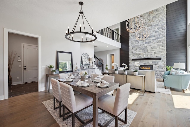 dining room with hardwood / wood-style flooring, a stone fireplace, and a high ceiling