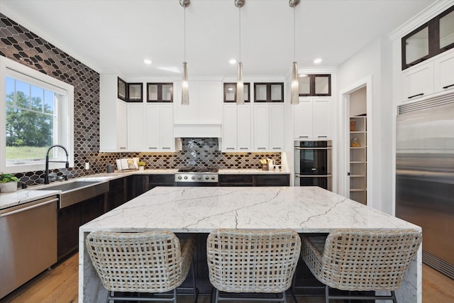 kitchen with light stone counters, appliances with stainless steel finishes, a center island, and pendant lighting