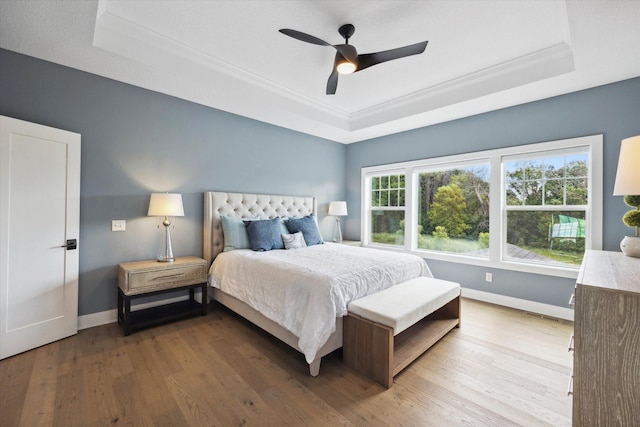 bedroom featuring ceiling fan, ornamental molding, a tray ceiling, and hardwood / wood-style floors