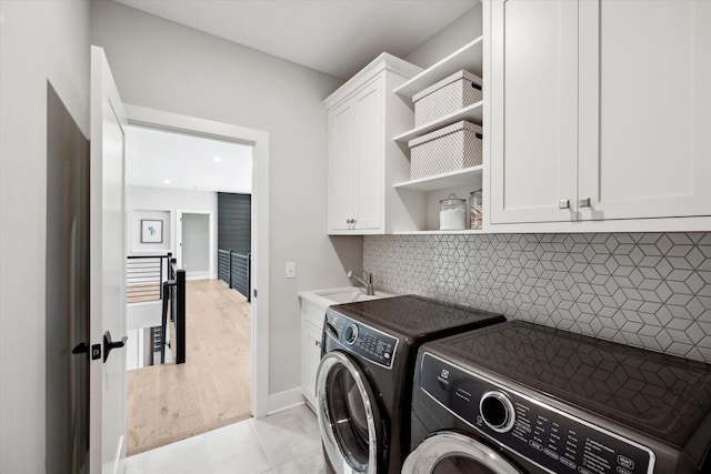 clothes washing area with cabinets, independent washer and dryer, sink, and light hardwood / wood-style flooring