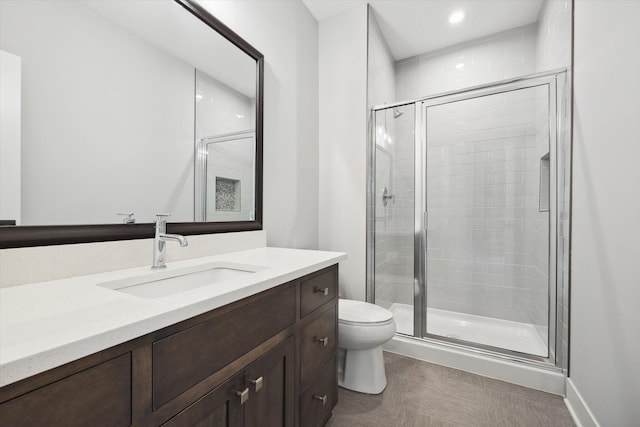 bathroom featuring vanity, a shower with shower door, and toilet