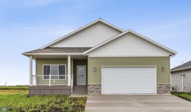 view of front of house with stone siding, a porch, concrete driveway, and an attached garage