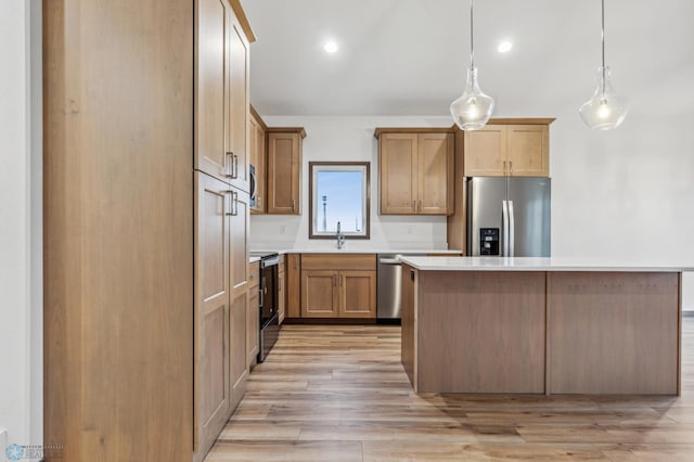 kitchen featuring a center island, light countertops, a sink, light wood finished floors, and stainless steel appliances