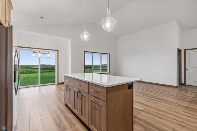 kitchen featuring a kitchen island, stainless steel refrigerator with ice dispenser, hanging light fixtures, light countertops, and light wood-style floors