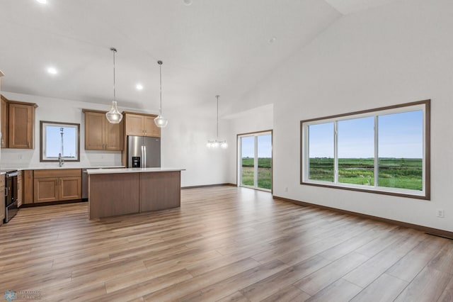 kitchen with a center island, light countertops, light wood finished floors, a chandelier, and stainless steel appliances