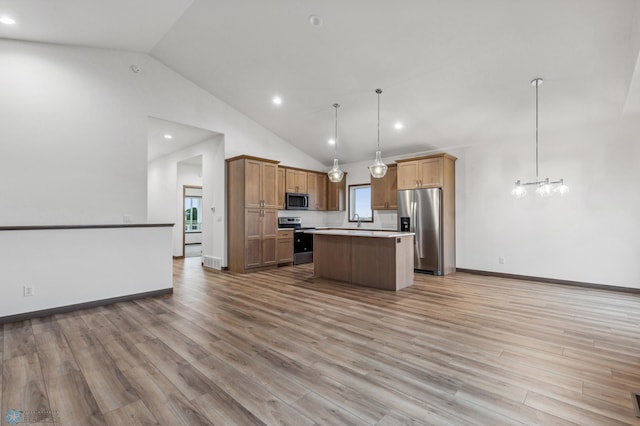 kitchen with appliances with stainless steel finishes, light countertops, light wood-style flooring, a center island, and open floor plan