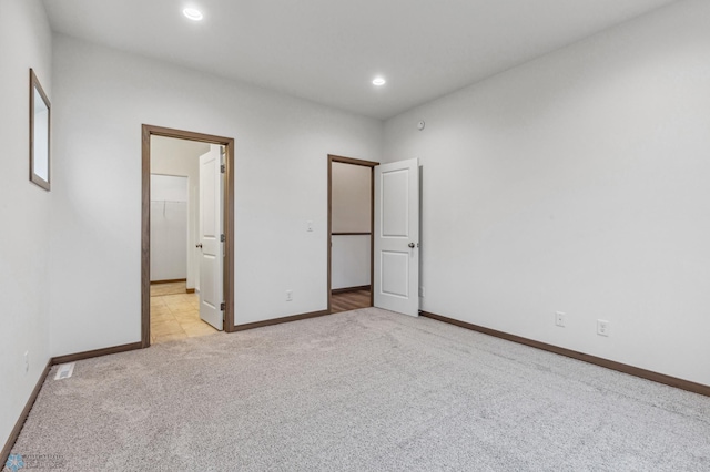 unfurnished bedroom with a closet, light carpet, baseboards, recessed lighting, and a spacious closet