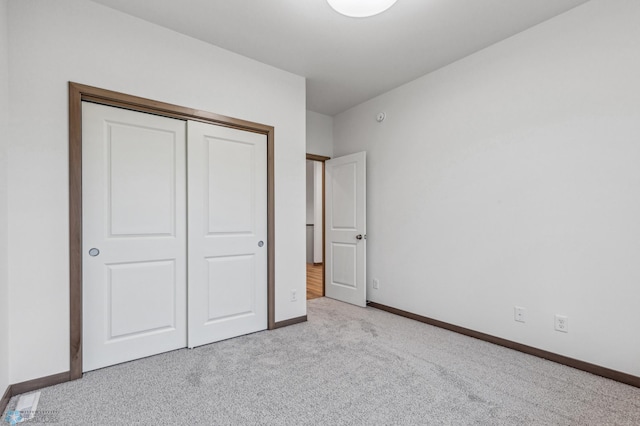 unfurnished bedroom featuring carpet floors, baseboards, and a closet