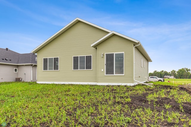 back of house with central air condition unit and a lawn