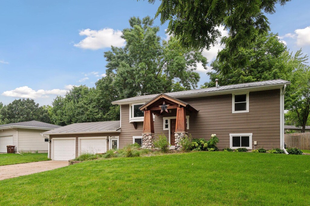 415 Adams Dr W, Norwood Young America, MN 55397 - raised ranch with concrete driveway, metal roof, a front lawn, and a garage