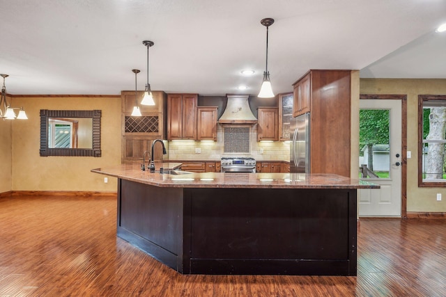 kitchen with light stone counters, pendant lighting, stainless steel appliances, custom range hood, and dark hardwood / wood-style flooring