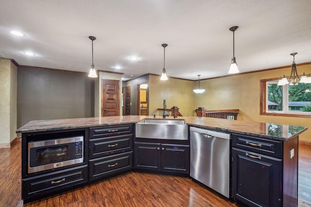 kitchen with appliances with stainless steel finishes, a kitchen island, dark wood-type flooring, and decorative light fixtures