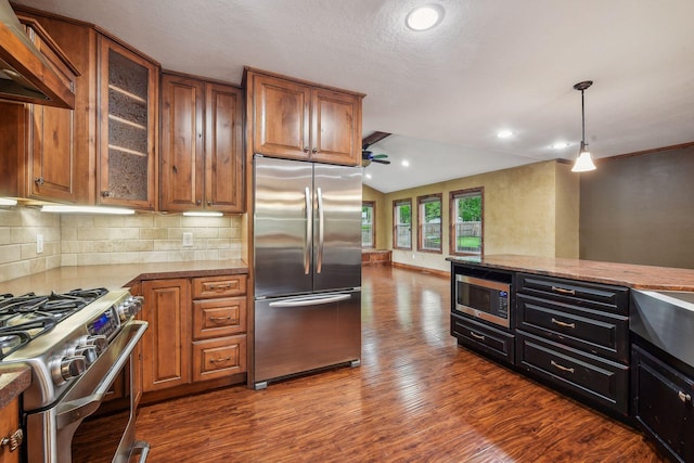 kitchen featuring backsplash, hardwood / wood-style flooring, appliances with stainless steel finishes, custom range hood, and light stone countertops