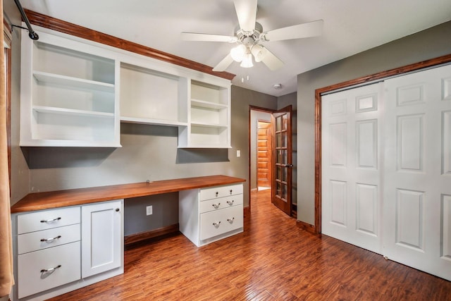 unfurnished office featuring ceiling fan, light wood-type flooring, and built in desk