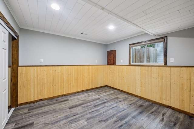 spare room featuring ornamental molding, wooden walls, wood ceiling, and wood-type flooring