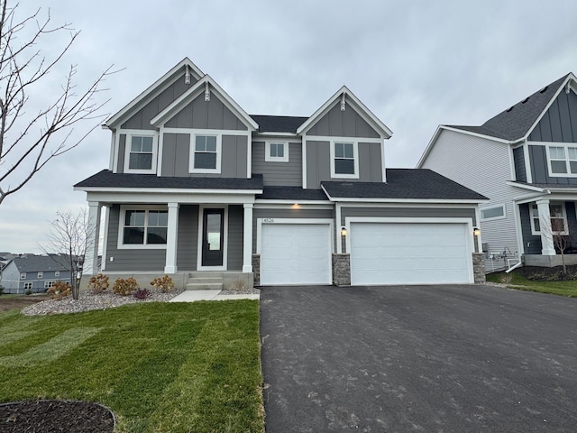 view of front of house featuring asphalt driveway, a front lawn, board and batten siding, a porch, and a garage