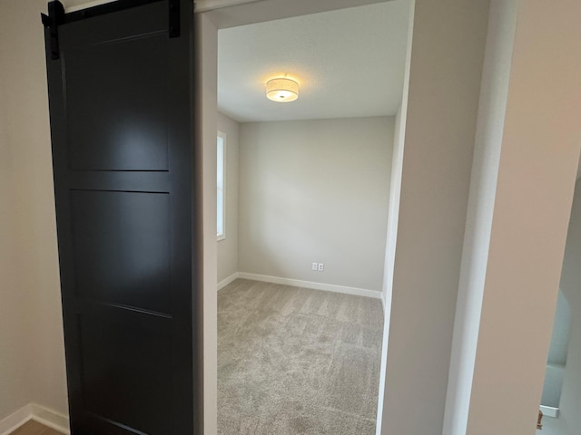 empty room with a barn door and light carpet