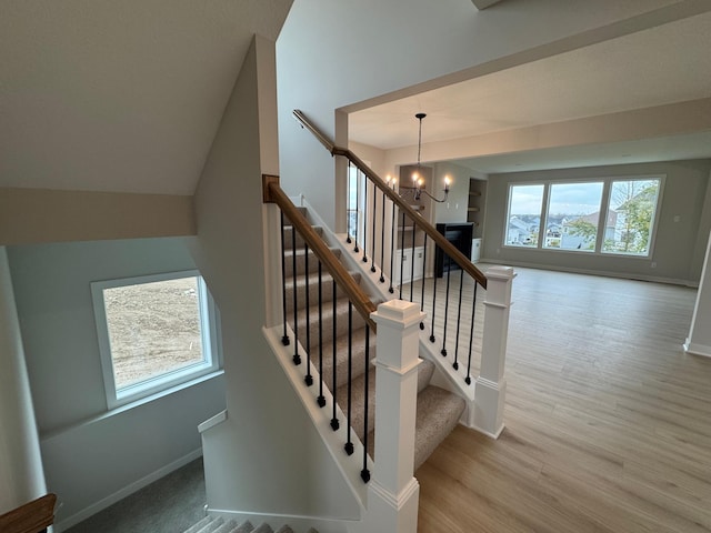 stairs featuring wood-type flooring and a chandelier