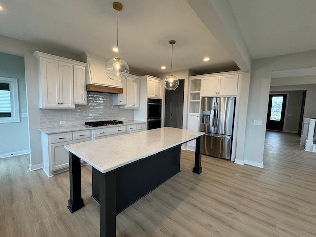 kitchen featuring white cabinets, stainless steel appliances, hanging light fixtures, and premium range hood