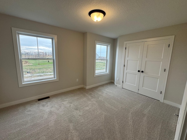 unfurnished bedroom with a textured ceiling, carpet, baseboards, and a closet