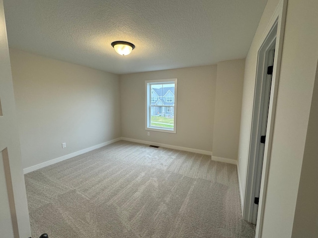 carpeted empty room featuring a textured ceiling and baseboards