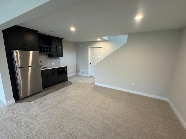 kitchen featuring tasteful backsplash, light carpet, and stainless steel refrigerator