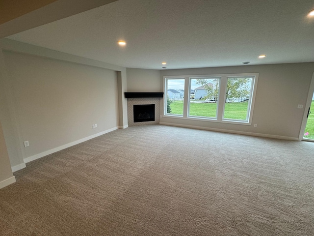 unfurnished living room with carpet floors, baseboards, recessed lighting, and a fireplace