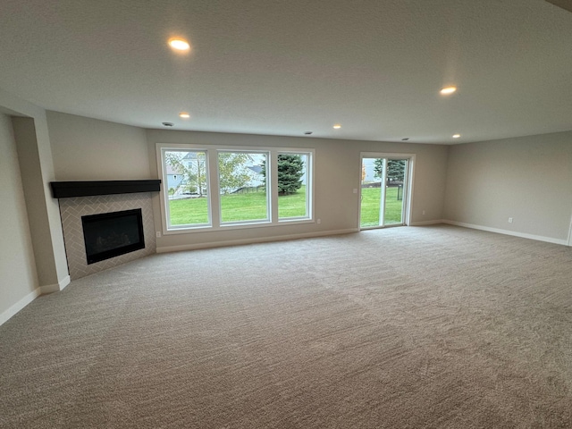 unfurnished living room featuring light carpet, a textured ceiling, and a tile fireplace