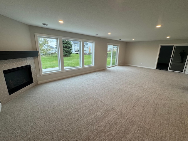 unfurnished living room featuring recessed lighting, carpet flooring, a fireplace, and baseboards