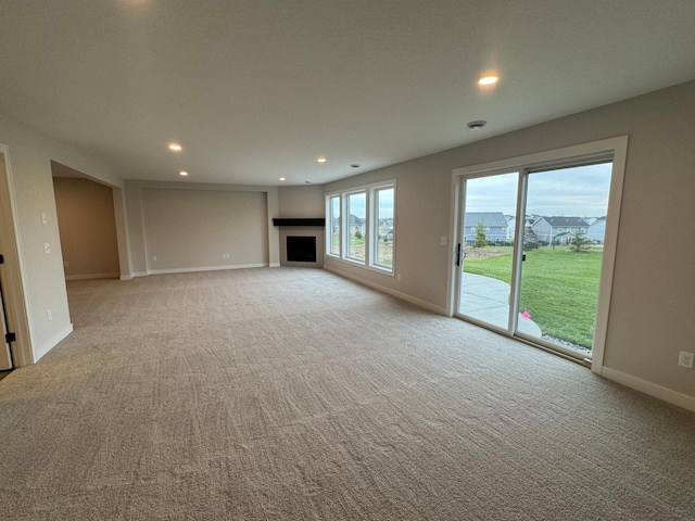 unfurnished living room featuring light carpet, a fireplace, recessed lighting, and baseboards