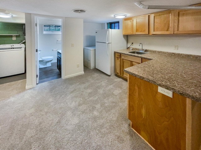 kitchen with a textured ceiling, light colored carpet, sink, washer / dryer, and white fridge