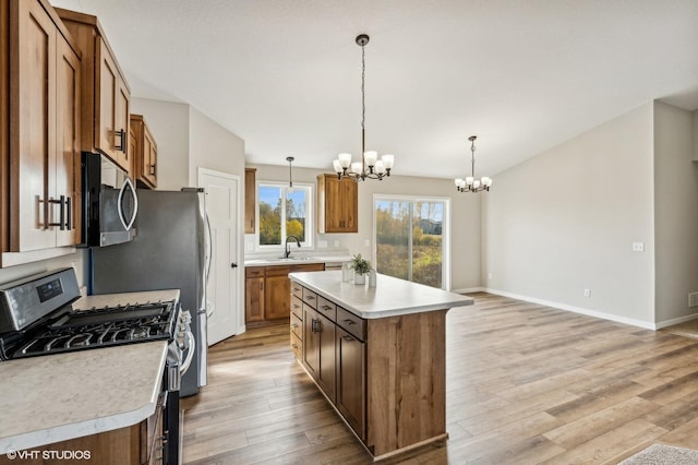 kitchen with stainless steel appliances, hanging light fixtures, light wood-type flooring, and a kitchen island