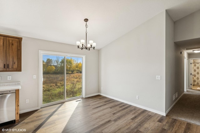 unfurnished dining area with hardwood / wood-style floors, a notable chandelier, and lofted ceiling