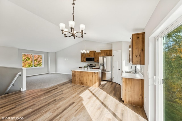 kitchen featuring a kitchen island, appliances with stainless steel finishes, pendant lighting, sink, and vaulted ceiling