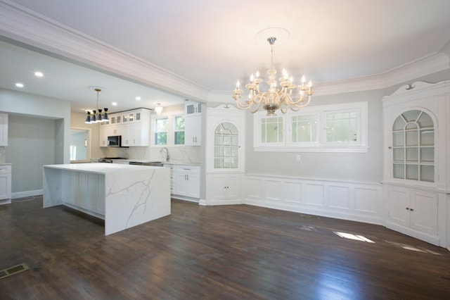 kitchen featuring ornamental molding, white cabinetry, hanging light fixtures, sink, and dark wood-type flooring