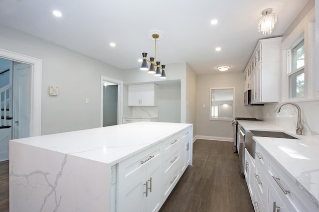 kitchen featuring light stone countertops, dark hardwood / wood-style floors, a kitchen island, white cabinets, and pendant lighting