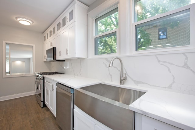 kitchen featuring light stone counters, backsplash, appliances with stainless steel finishes, dark hardwood / wood-style floors, and white cabinets