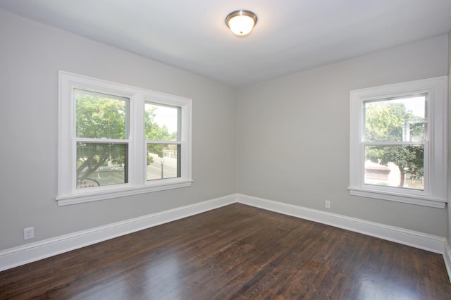 spare room with a wealth of natural light and dark hardwood / wood-style flooring