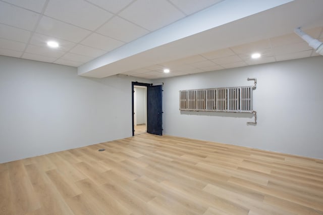 basement with a paneled ceiling and light hardwood / wood-style flooring