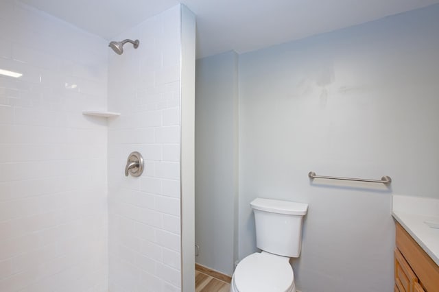 bathroom featuring hardwood / wood-style flooring, vanity, toilet, and tiled shower