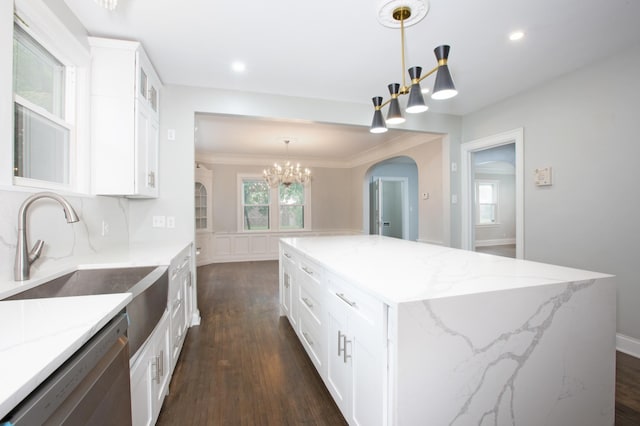 kitchen featuring a center island, an inviting chandelier, stainless steel dishwasher, pendant lighting, and white cabinetry